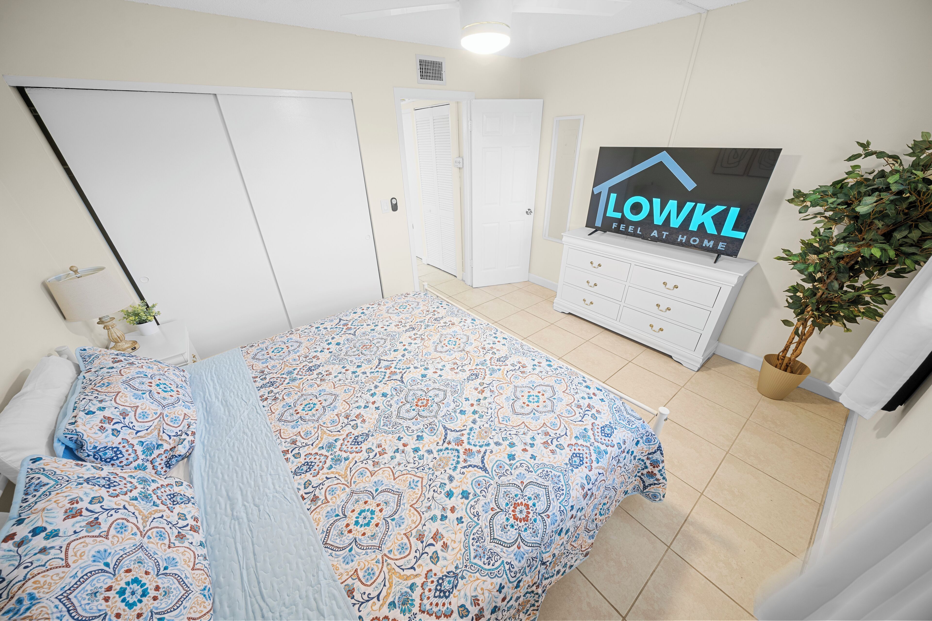 Um quarto com cama, penteadeira, espelho e um aviso na parede.