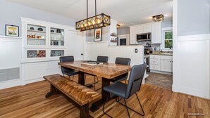 A modern kitchen with white cabinets, a wooden dining table, and black chairs.