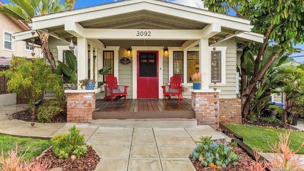 A house with a front porch, two red Adirondack chairs, and a brick column.