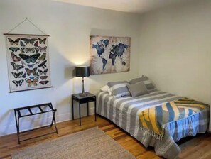 A bedroom with a bed, a nightstand, a lamp, a rug, and two wall art pieces. - Historic Craftsman Home in South Park near Zoo, Balboa Park, sleeps 8! (San Diego)