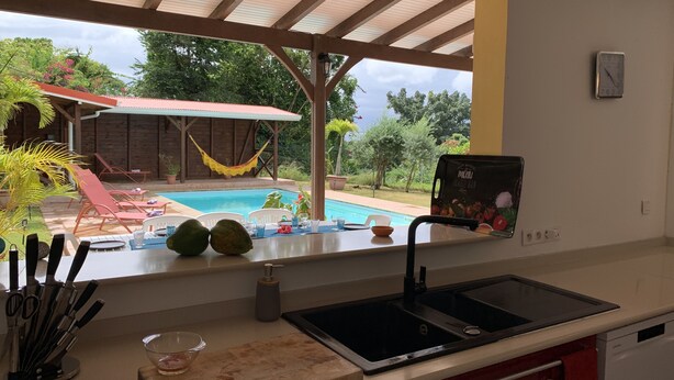 A kitchen with a view of a swimming pool, outdoor seating, and a hammock. - Welcome to casa fall, a large family villa in the rainforest. Enjoyyyyy!!! (Fort-de-France)
