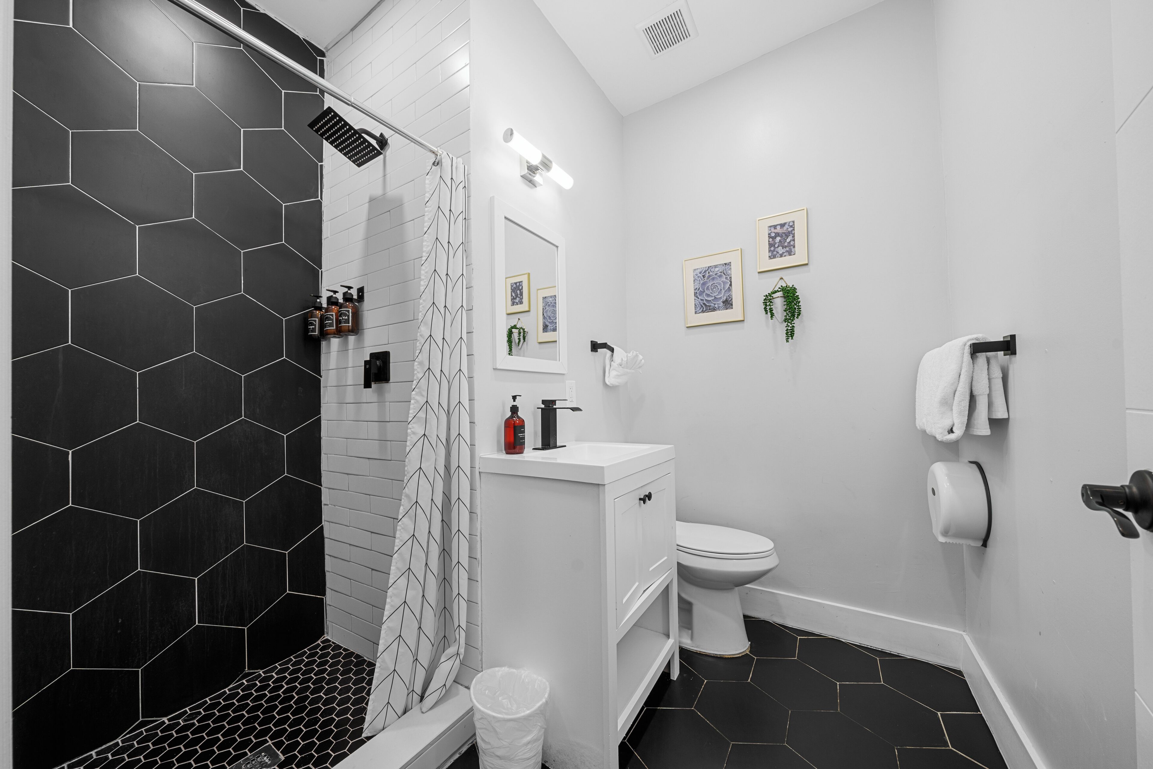 A modern bathroom with a shower, toilet, and sink.