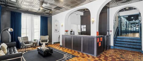A modern lobby with a reception desk, seating area, and a patterned floor.