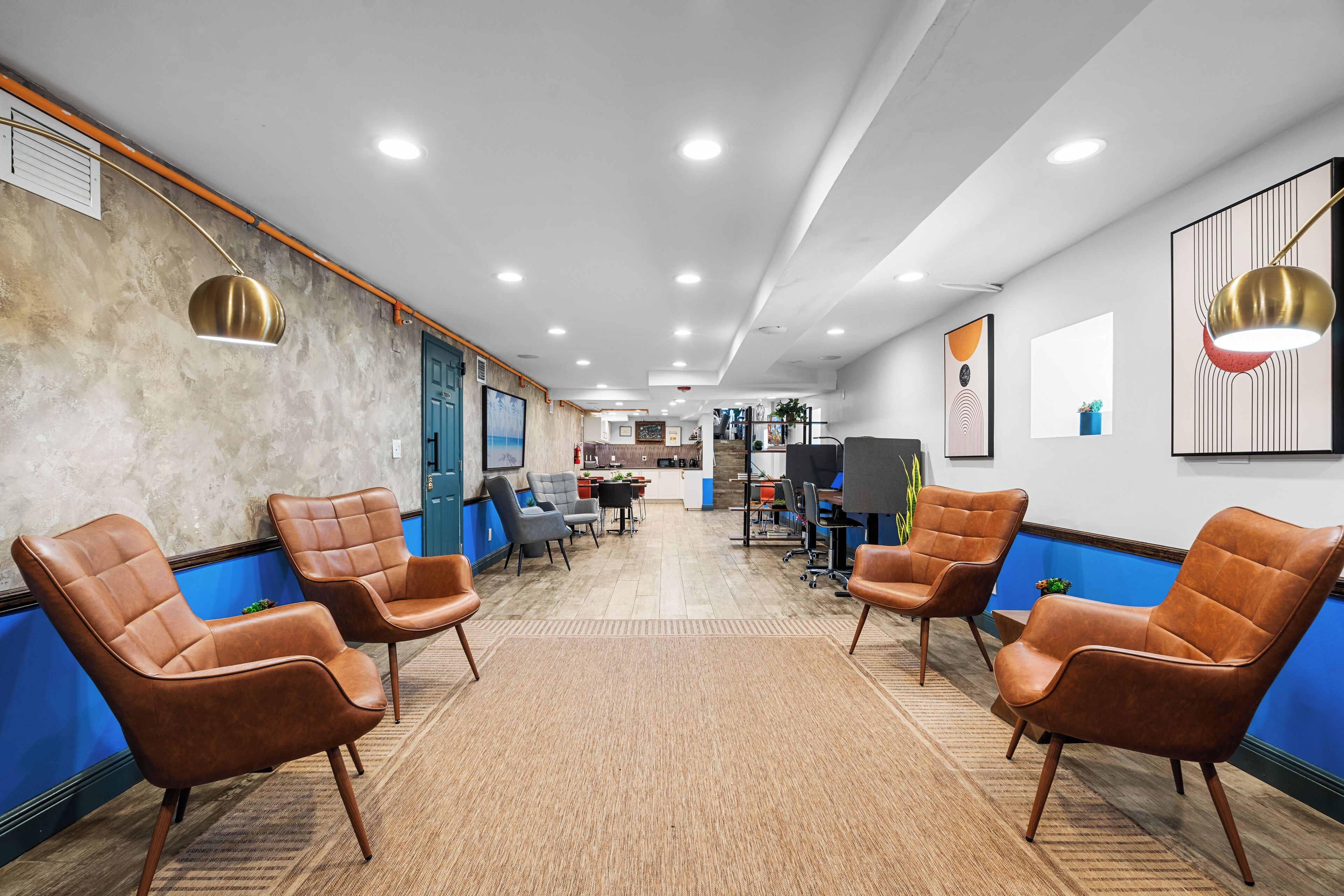 Un espace de bureau moderne doté de fauteuils en cuir, d’un coin cuisine et d’une salle de réunion.