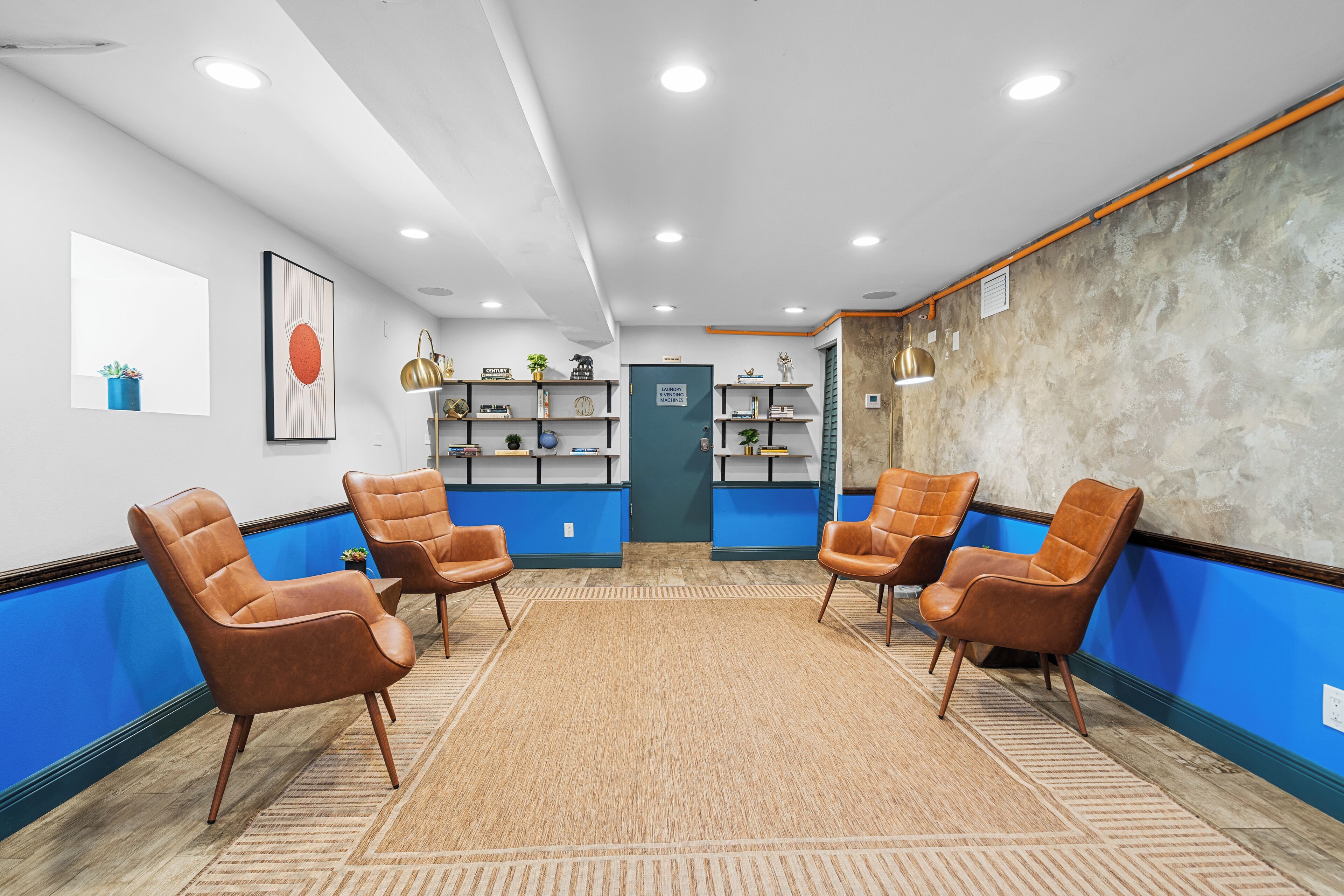 Un espace d’accueil comprenant quatre fauteuils en cuir marron, une décoration aux couleurs bleu et blanc, et un comptoir de réception.