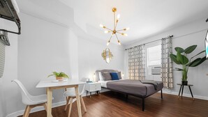 Une chambre moderne avec un lit, un bureau et une chaise. Il y a une plante sur le bureau et une plante en pot à côté du lit.