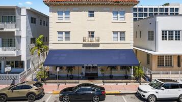 A building with a blue awning, a staircase, and a parking lot with cars.