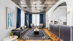 Un salon moderne avec un canapé, des fauteuils, une table basse et un sol à motifs.