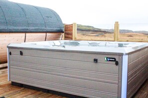 Un bain à remous de spa doté d’une terrasse en bois et offrant une vue sur le paysage.