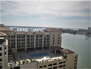 Un hotel con piscina en la azotea, varios balcones y vistas a un río con un puente a lo lejos.