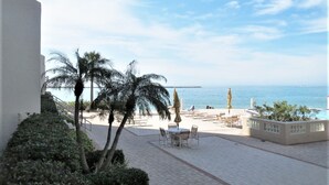 A terrace with a view of the sea, palm trees, and outdoor seating. - Beautiful Penthouse Style on Clearwater Beach (Clearwater)