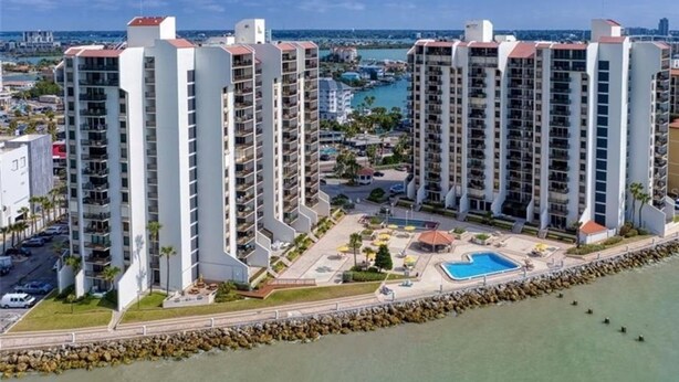 A high-rise residential building with multiple balconies, a swimming pool, and a marina in the background. - Beautiful Penthouse Style on Clearwater Beach (Clearwater)