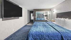 A modern hotel room with a large bed, a flat-screen TV mounted on the wall, and a bathroom visible through an open door. - Hotel Opus Bronx (Bronx)