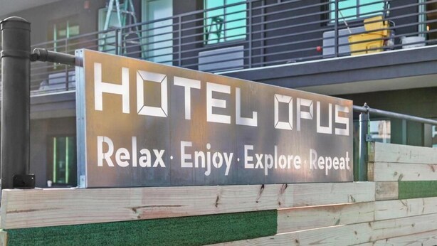 A sign for HOTEL OFUS with the tagline "Relax · Enjoy · Explore · Repeat." - Hotel Opus Bronx (Bronx)