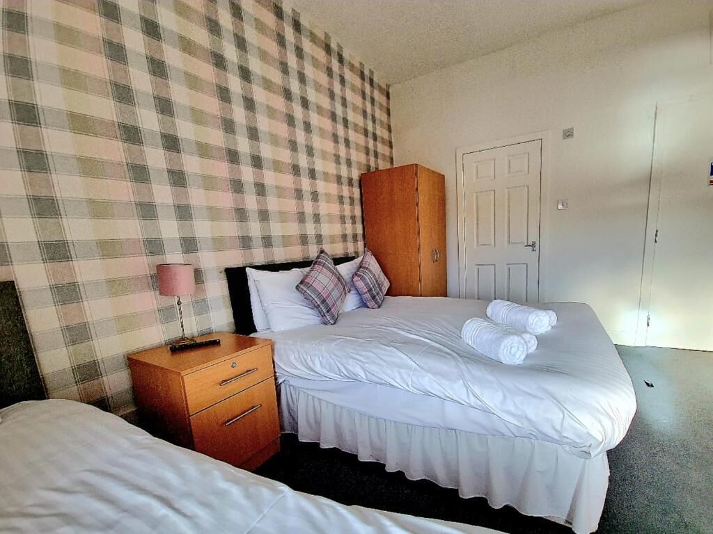 Una habitación de hotel con cama, mesita de noche, armario y puerta.