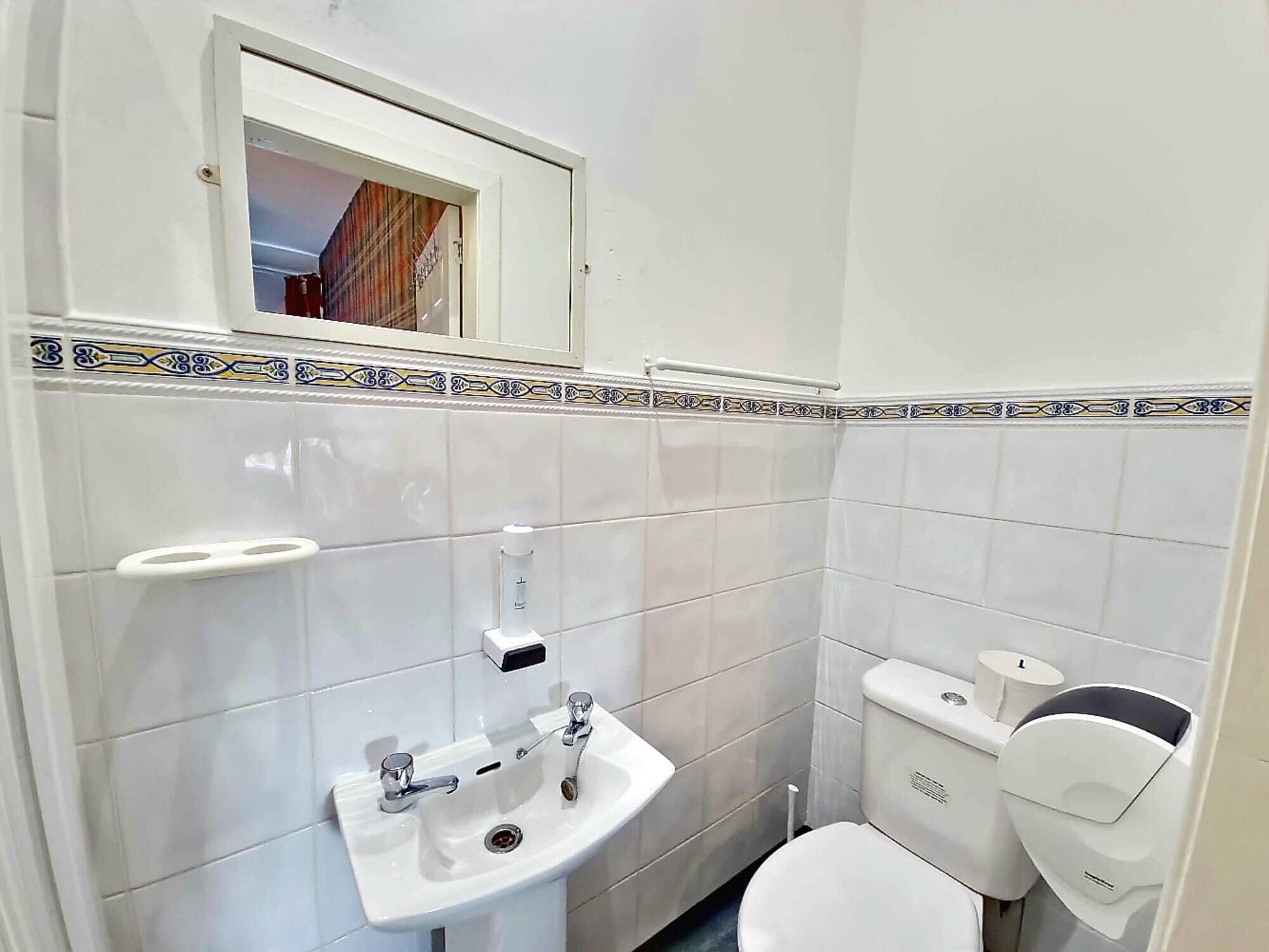 A small bathroom with a white sink, a toilet, and a window above the sink.