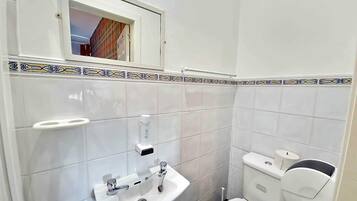 A small bathroom with a white sink, a toilet, and a window above the sink.