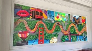 Un mural colorido con puntos de referencia e iconos emblemáticos, incluyendo un autobús rojo, un corazón y un puente.