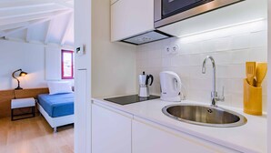 Una cocina compacta con un lavamanos de acero inoxidable, una tetera y un microondas.