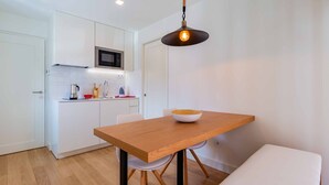 Una cocina moderna con armarios blancos, una mesa de comedor de madera y una lámpara colgante.