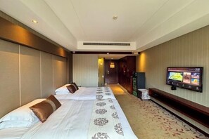 A hotel room with two beds, a television mounted on the wall, and a carpeted floor.