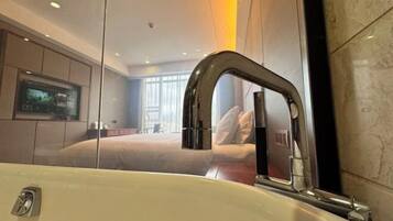 A modern bathroom with a large mirror, a sink, and a television mounted on the wall.