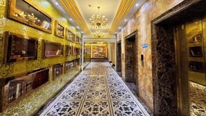 A luxurious hallway with ornate mirrors, a chandelier, and marble flooring.