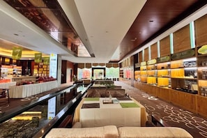 A hotel lobby with a central water feature, seating area, and a bar with shelves of bottles.