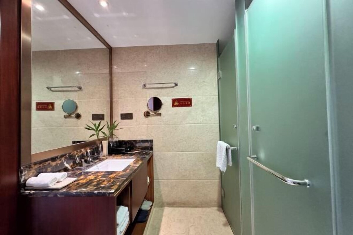 A modern bathroom with a marble vanity, a sink, a mirror, and a towel rack.