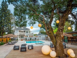 A pool area with lounge chairs and a large tree. - The Ruse (Healdsburg)