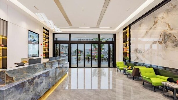 A modern lobby with a marble reception desk, green seating area, and a large marble wall. - Zhenfeng Business Hotel (Ningbo)