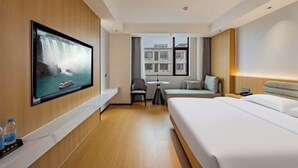 A hotel room with a large bed, a TV mounted on the wall, a small table, and a window with a view of buildings. - Zhenfeng Business Hotel (Ningbo)