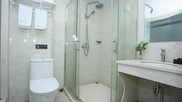 A modern bathroom with a glass-enclosed shower, a toilet, and a sink with a mirror.