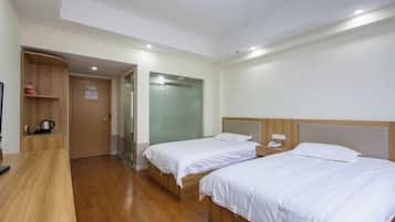 A hotel room with two beds, a wooden desk, a glass shower, and a wooden wardrobe.
