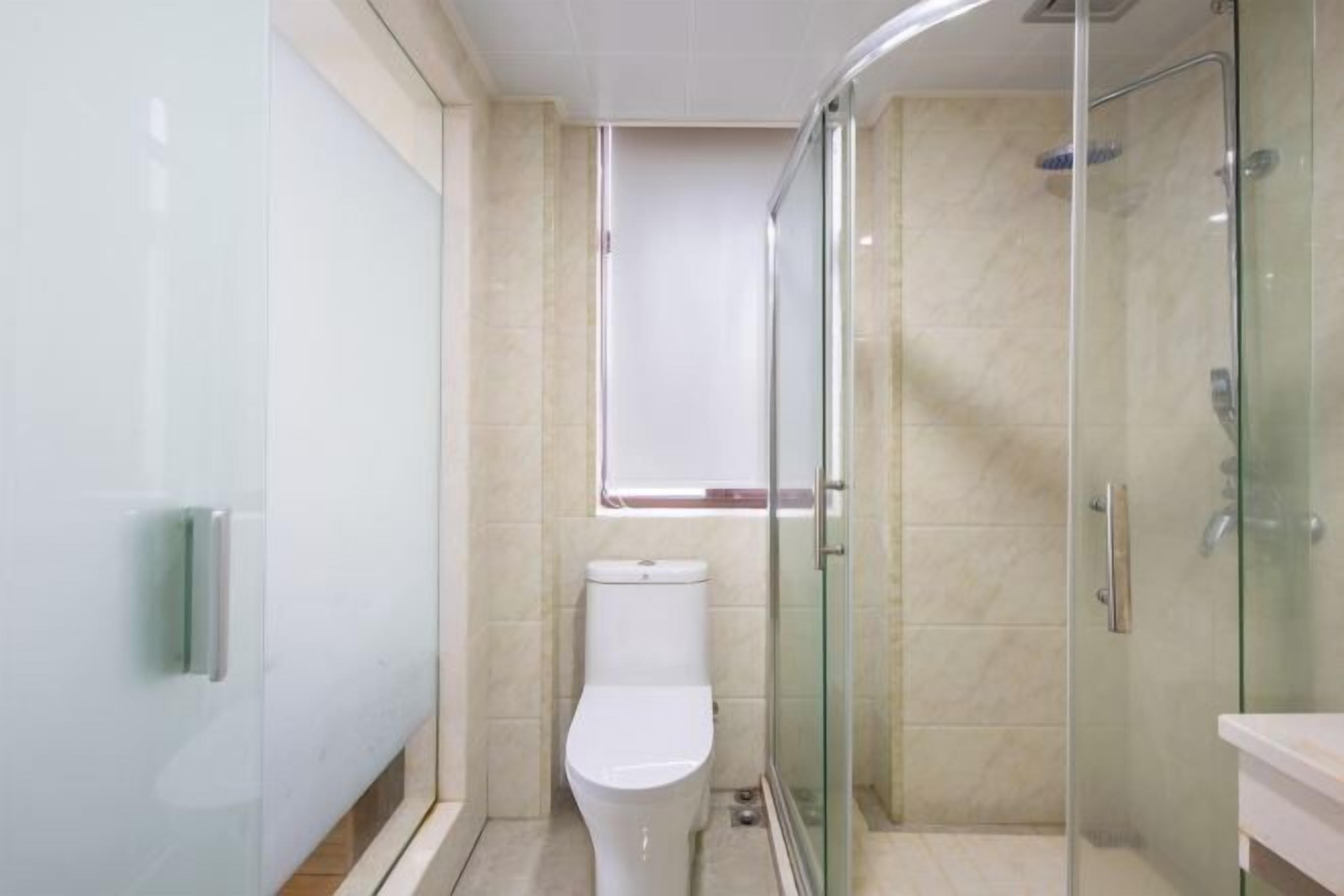 Un baño moderno con cabina de ducha de vidrio, inodoro y tocador con espejo.