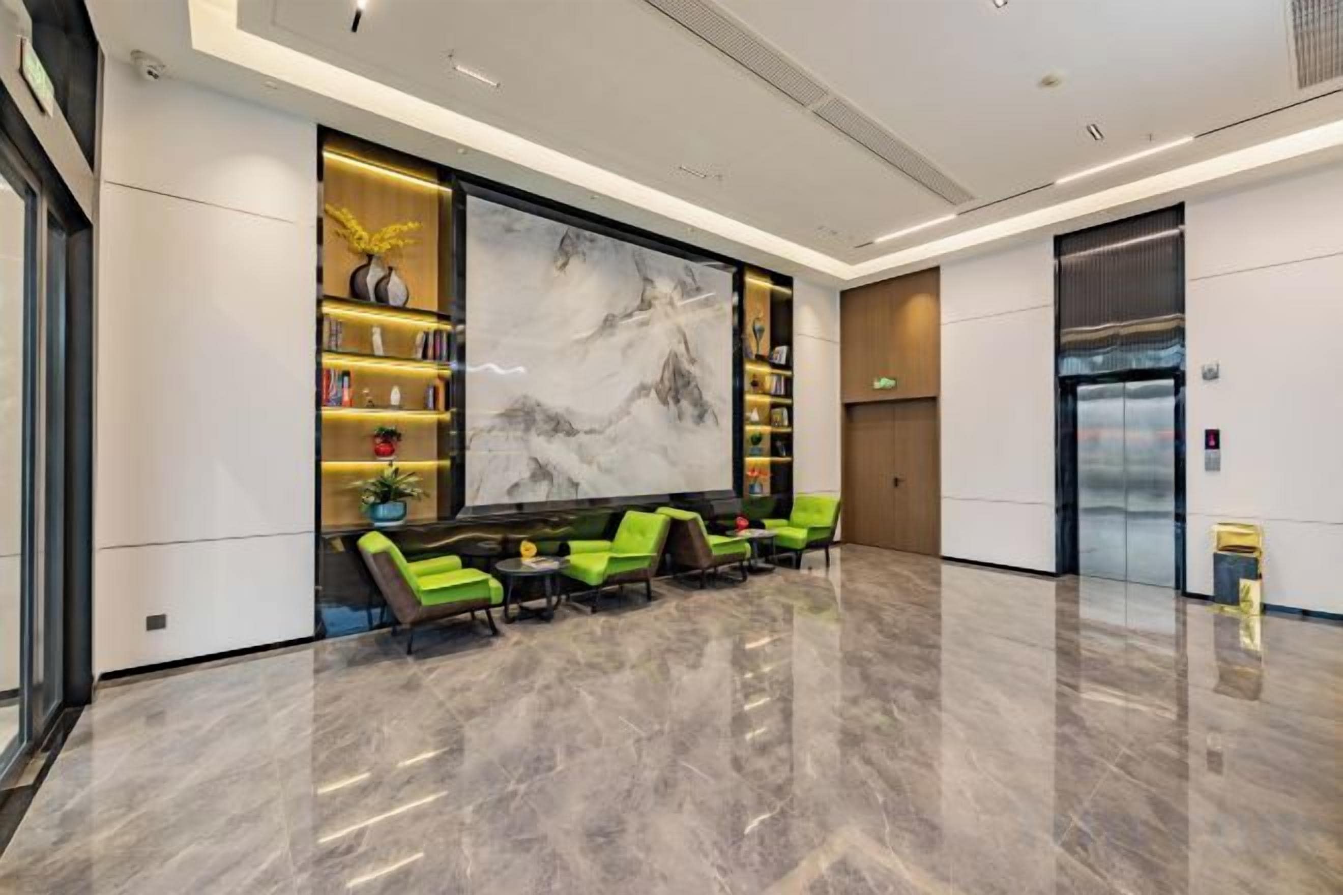 A lobby with a marble floor, seating area, bookshelves, a large artwork, and an elevator.