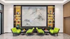 A lobby with a large abstract painting, green seating, and shelves with books and decorative items. - Zhenfeng Business Hotel (Ningbo)