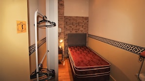 A narrow room with a single bed, a hanging coat rack, and a small table with a lamp. - Luxurious and charming central loft, unique!! (Buenos Aires)