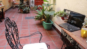 A patio area with a laptop on a table, surrounded by potted plants and a chair. - Luxurious and charming central loft, unique!! (Buenos Aires)