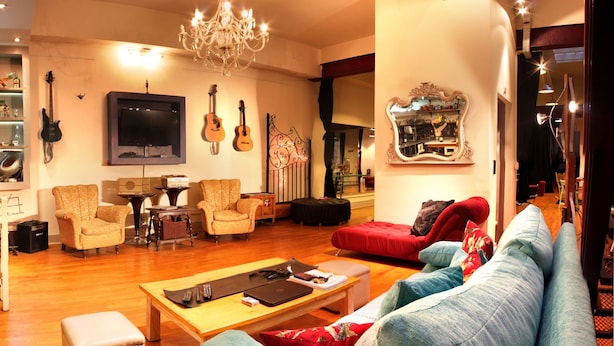 A living room with a sofa, armchairs, a coffee table, a TV, guitars, and a mirror. - Luxurious and charming central loft, unique!! (Buenos Aires)