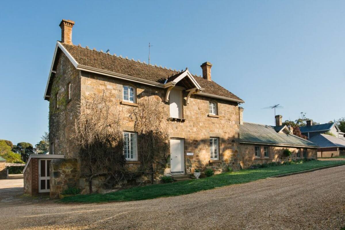 A stone house with a sloped roof, a chimney, and a small front porch.