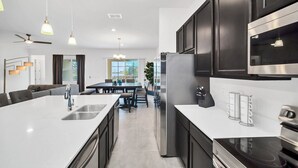 Cozinha moderna com ilha central, eletrodomésticos de aço inoxidável e área de refeições com vista.