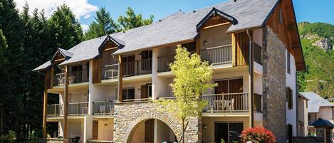 A multi-story hotel with balconies, stone archways, and a parking lot.