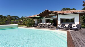 A modern house with a swimming pool, a patio with chairs, and a covered outdoor area. - Belle villa avec piscine privée | Près de la plage (Moliets)