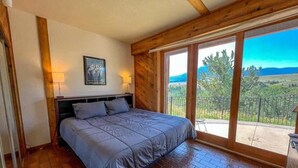 Une chambre à coucher avec un lit, des murs en bois, une grande fenêtre et une vue sur l’extérieur.