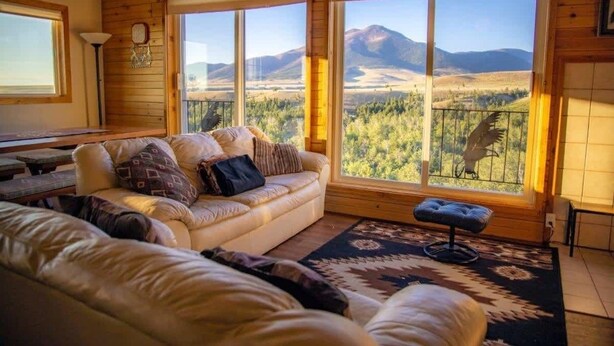 Une pièce chaleureuse avec une grande fenêtre donnant sur les montagnes, un canapé confortable et une petite table.