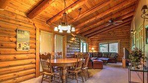 A log cabin interior with a dining area, a sofa, and a television. - Bison Turf- Hot Tub-Views - Close to Downtown (Red Lodge)