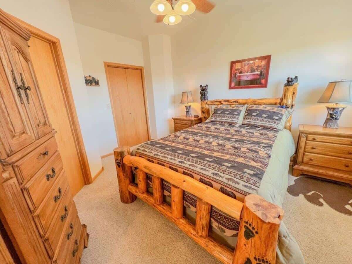 A bedroom with a wooden bed frame, a dresser, a nightstand, and a lamp.