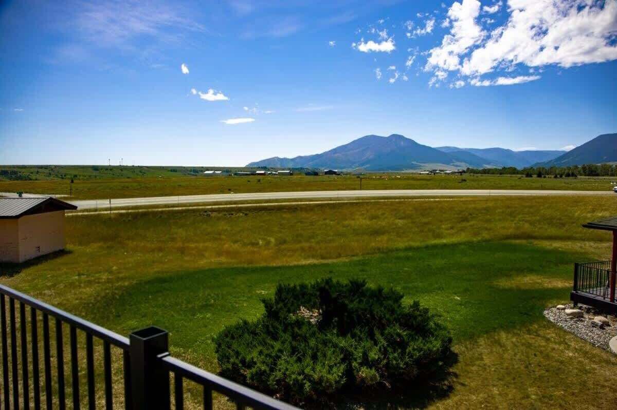 Un campo cubierto de hierba con un edificio pequeño y una montaña al fondo.