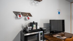 A kitchenette with a microwave, coffee maker, and a flat-screen TV.